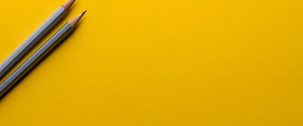 two gray pencils on yellow surface