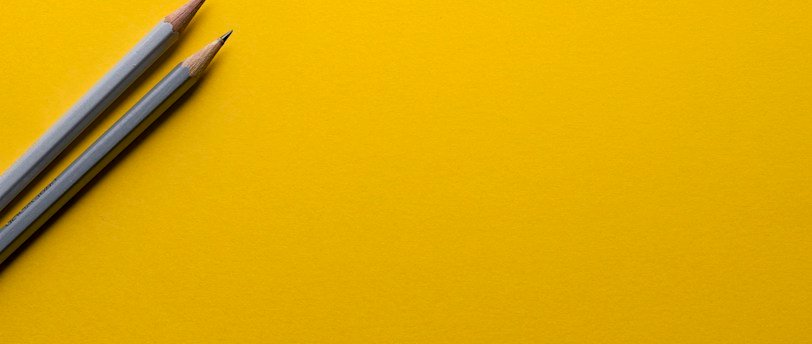 two gray pencils on yellow surface